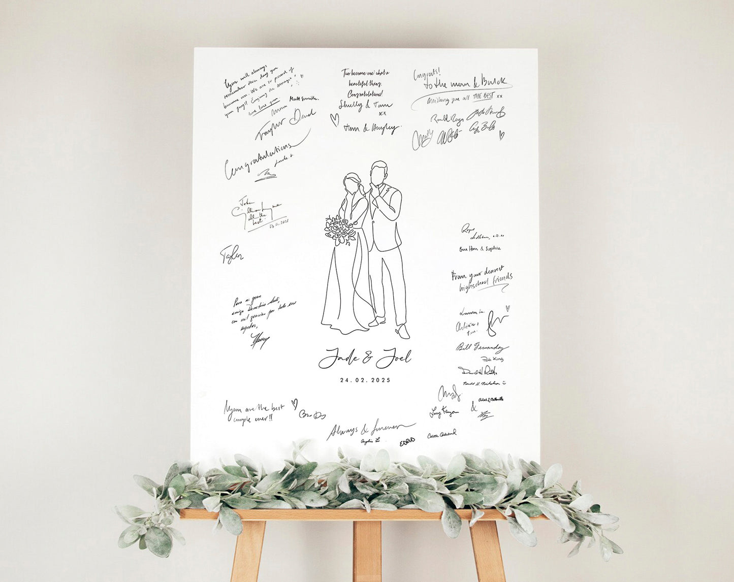 Wedding guest book poster with a custom line art drawing of the couple in the middle, mounted on a stand with greenery against a white wall