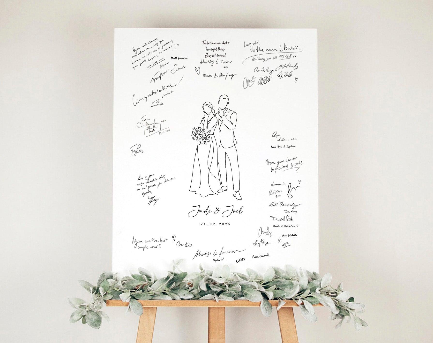 Wedding guest book poster with a custom line art drawing of the couple in the middle, mounted on a stand with greenery against a white wall