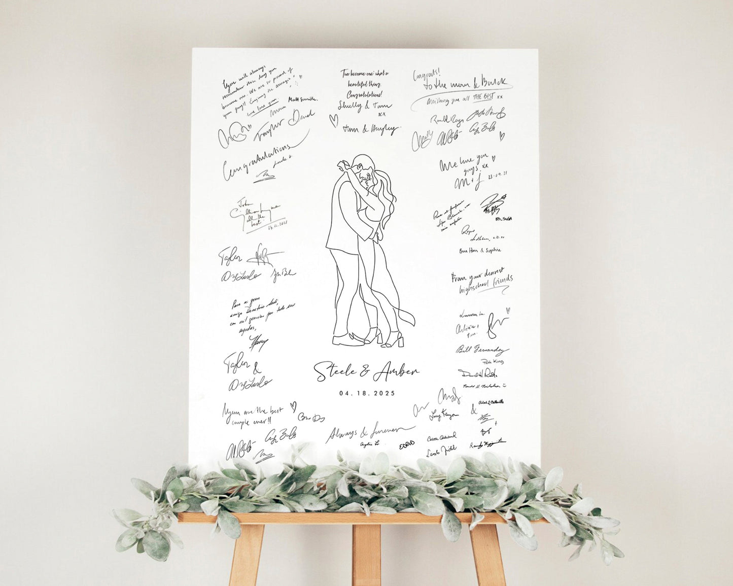 Wedding guest book poster mounted on easel decorated with eucalyptus leaves in front of an off-white wall