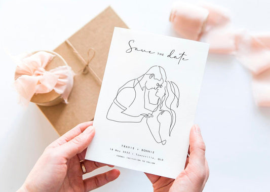 Hands holding a Save the date card with white background with a line art portrait of the couple in the middle
